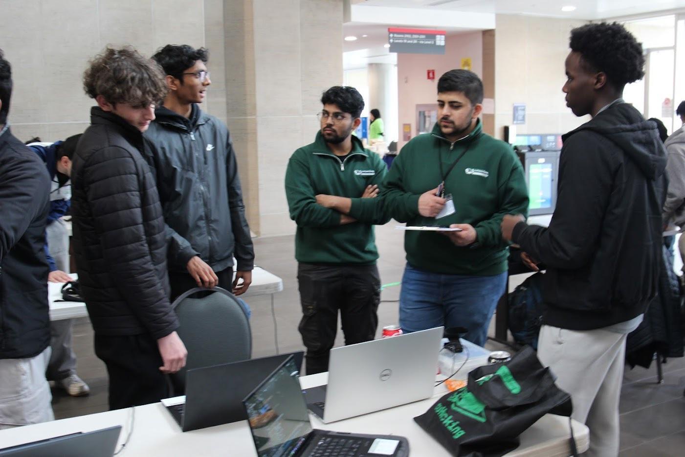 cuHacking organizers in green shirts helping attendees at their laptops